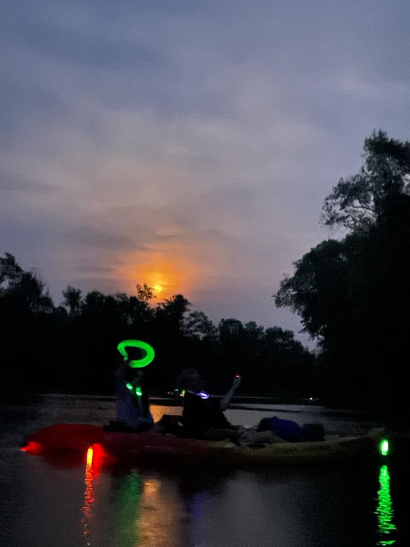 Friends paddle together as they kayak down the Auglaize River under the summer night's moonlight