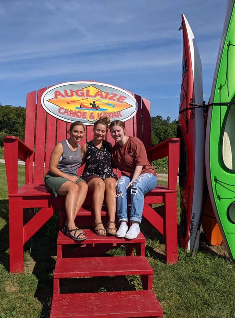 Friends pose for a photo on the famous giant Adirondack chair